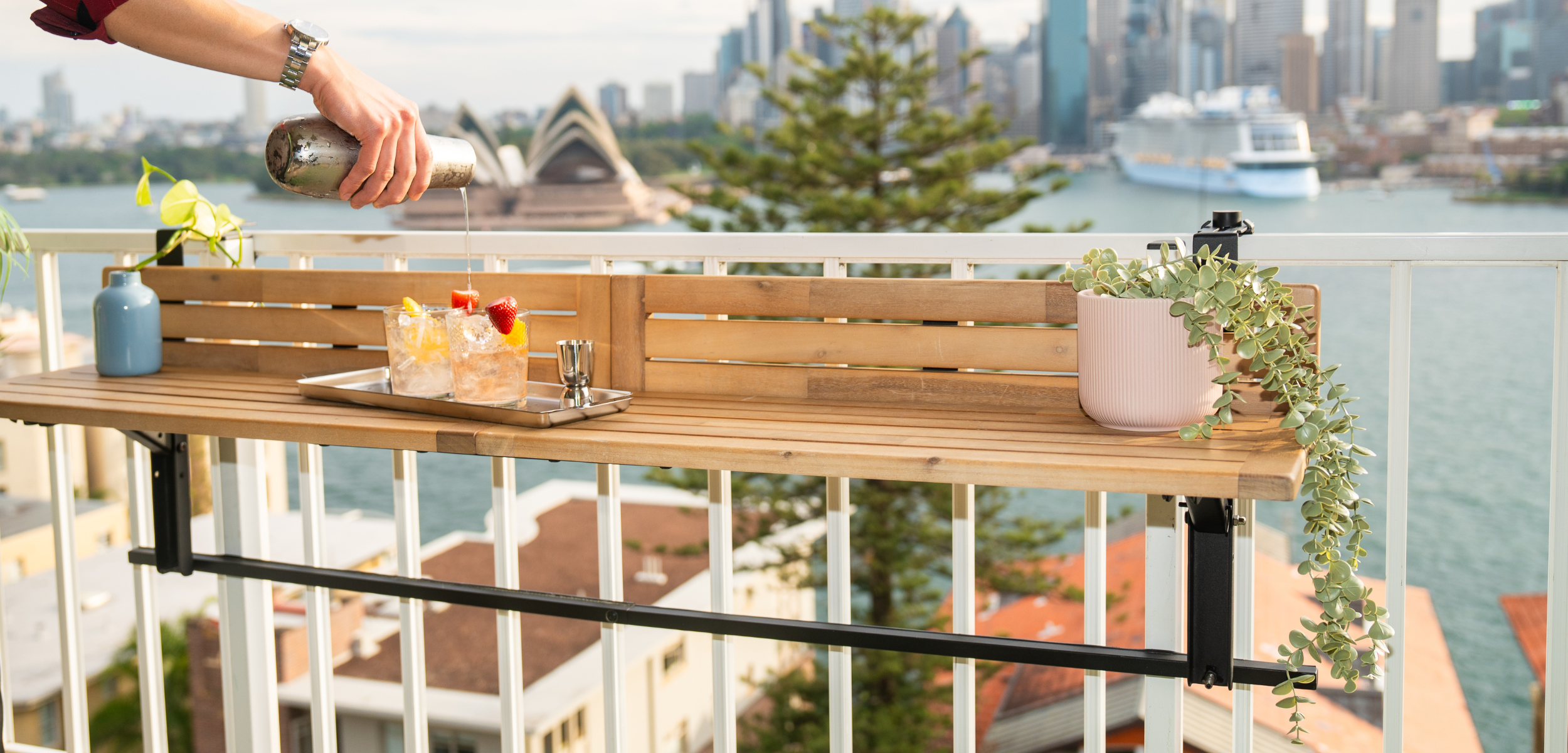 Acacia wood balcony bar table mounted on balcony railing featuring cocktails and plant decor with an Ocean view