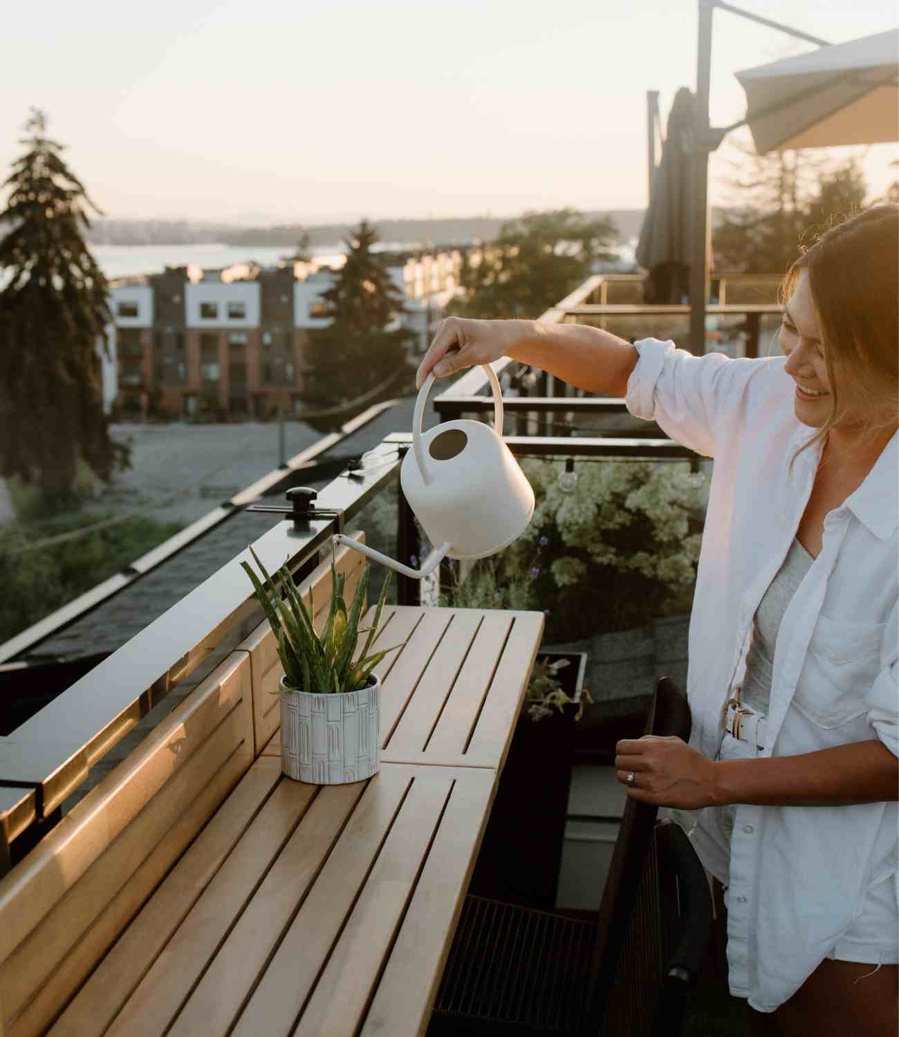 Women watering a plant on a Views Balcony Bar table