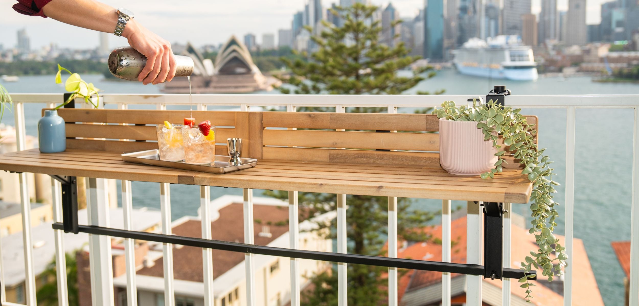 Acacia wooden folding balcony table on a balcony with a cityscape and waterfront view.